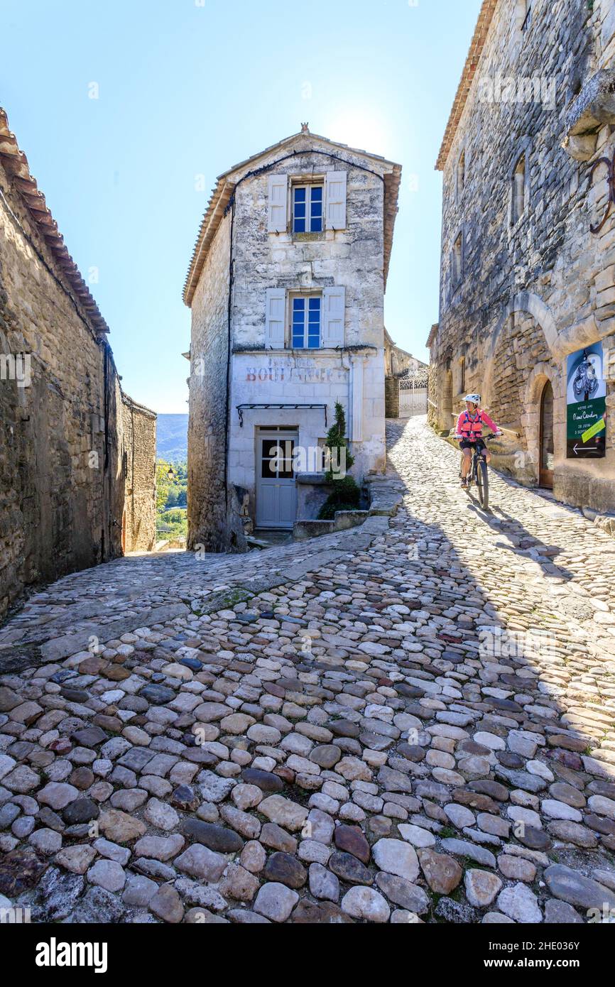 Francia, Vaucluse, Parc Naturel Regional du Luberon (Parco Naturale Regionale del Luberon), Lacoste, vicolo lastricato nel villaggio con un ciclista // Francia, va Foto Stock