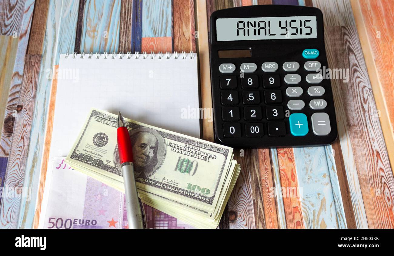 Analisi, il testo è scritto sul display della calcolatrice, su uno sfondo striped si trova un notebook con valuta Foto Stock