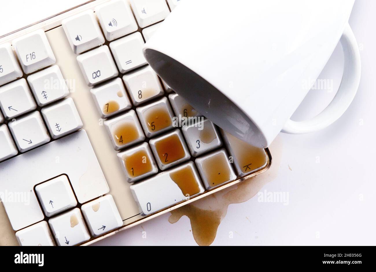 Il caffè si spillano sulla tastiera bianca del computer Foto Stock