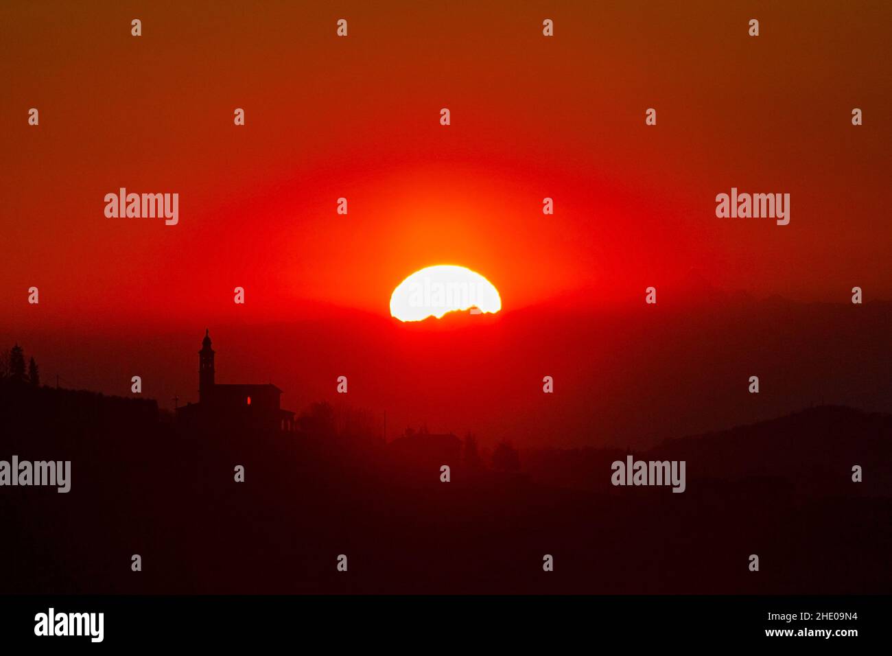 Tramonto dietro una chiesa sulle Alpi in inverno Foto Stock