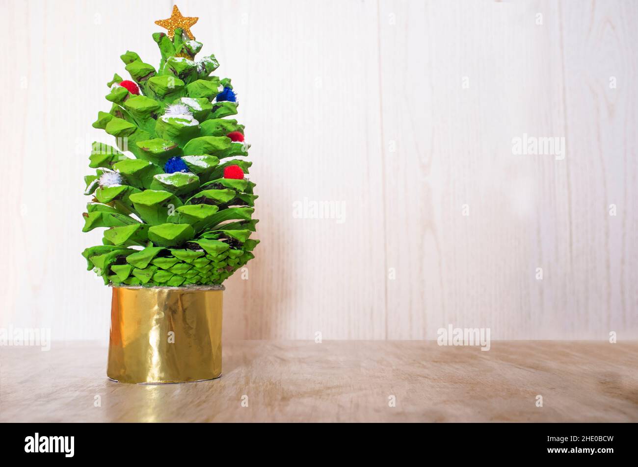 Albero di Natale con cono di pino dipinto. Artigianato di Natale fatto con parti della natura Foto Stock