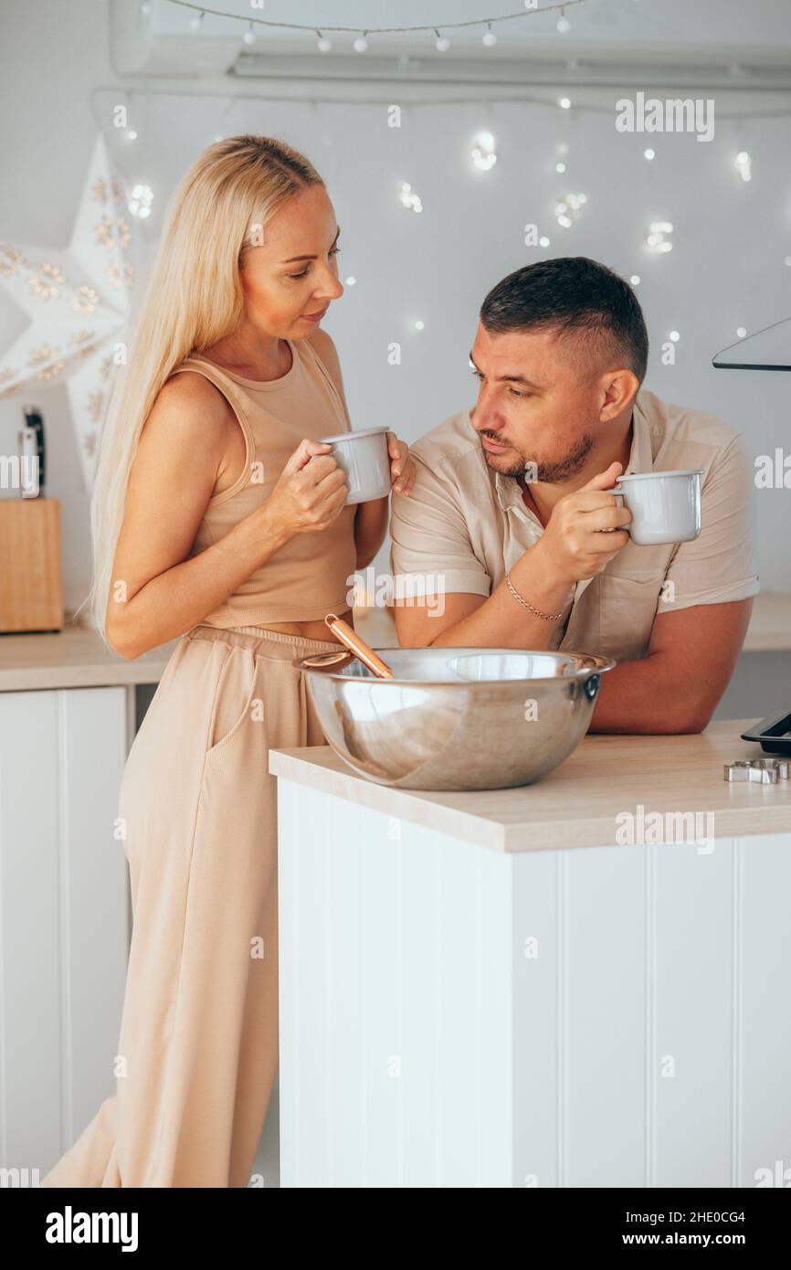 Coppia caucasica bere cioccolata calda mentre si prepara l'impasto per il pan di zenzero. Foto Stock