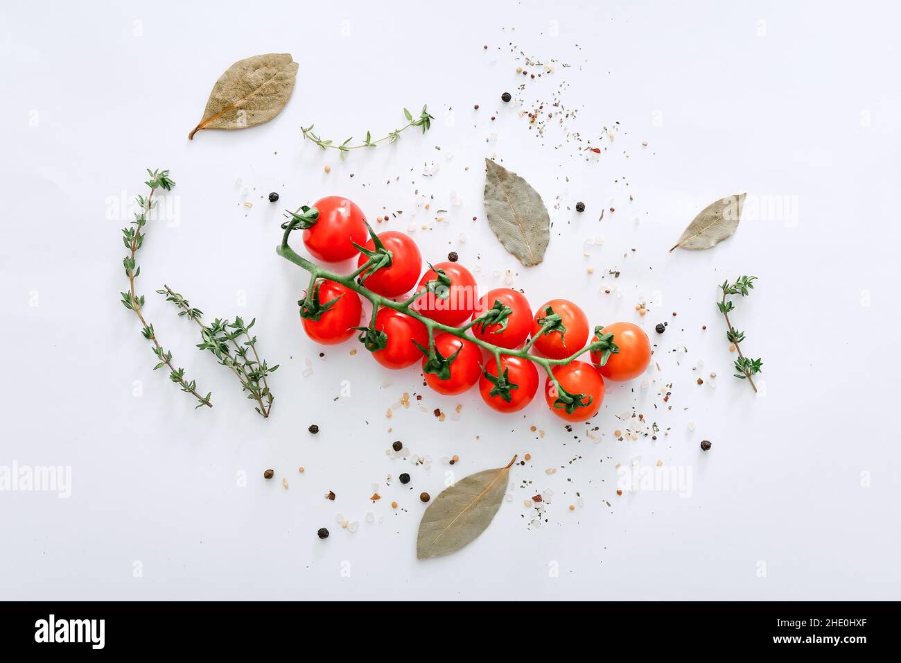 Spezie e pomodori su sfondo grigio chiaro, vista dall'alto. Foto Stock