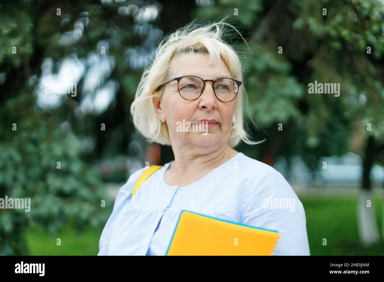 Bella adulta 35-40 anni donna d'affari che indossa occhiali in piedi tenere notepads guardare la macchina fotografica all'aperto Foto Stock