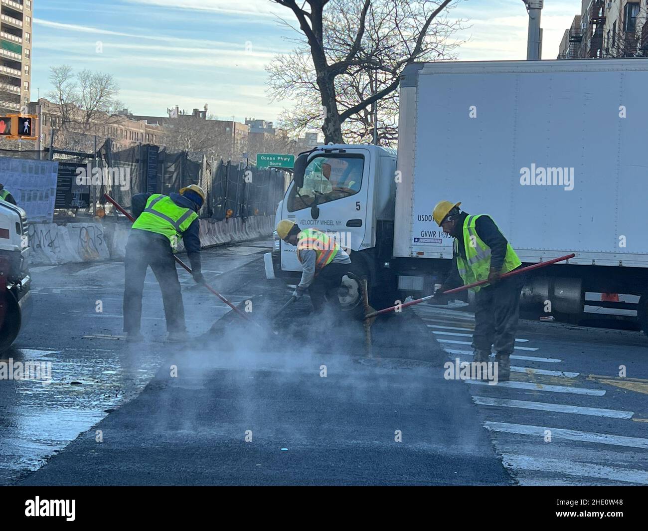 Gli operai della città catalizzano la superficie della strada dopo aver completato la sostituzione del tubo sotterraneo al mattino presto lungo Caton Avenue all'Ocean Parkway a Brooklyn, New York. Foto Stock