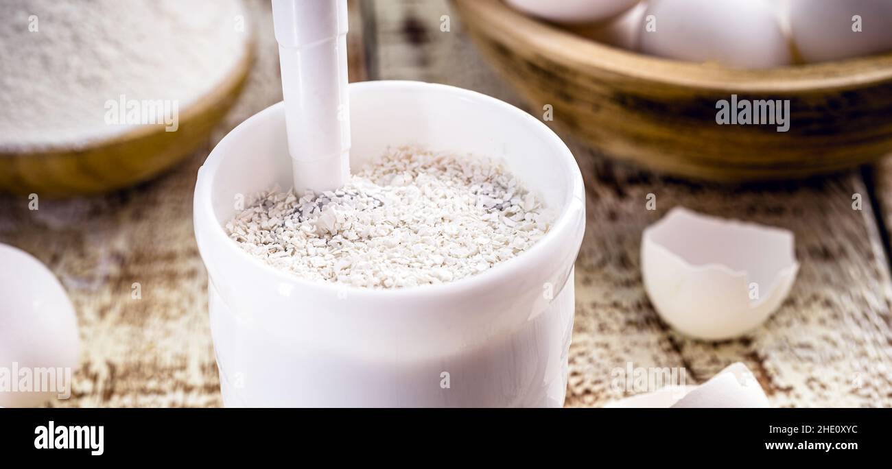 guscio di melanzane macinato in pestello di plastica, ingrediente di cottura, fonte di calcio per piante Foto Stock