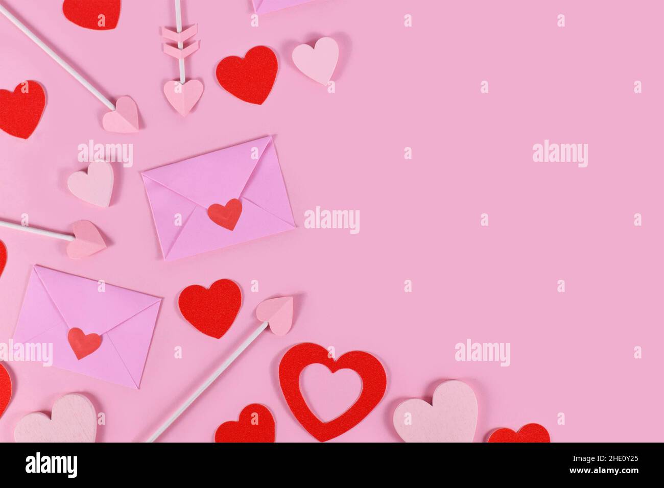 San Valentino piatto posato con lettere d'amore, frecce cupide e cuore rosso confetti su sfondo rosa Foto Stock