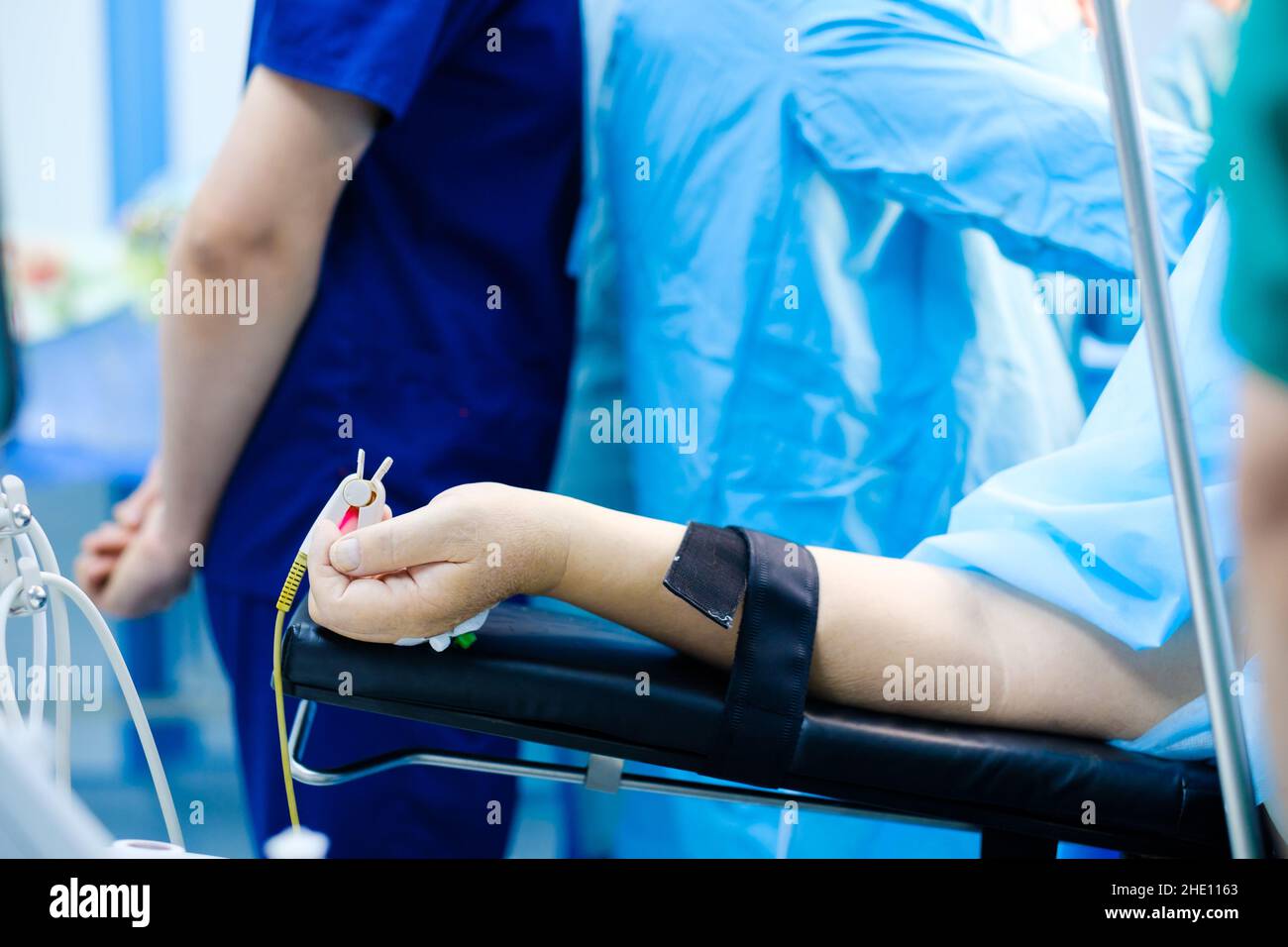La mano del paziente giacente sul tavolo operatorio. Messa a fuoco selettiva. Un pulsossimetro su un dito umano durante l'intervento chirurgico. Anestesia generale durante l'intervento chirurgico. Foto Stock