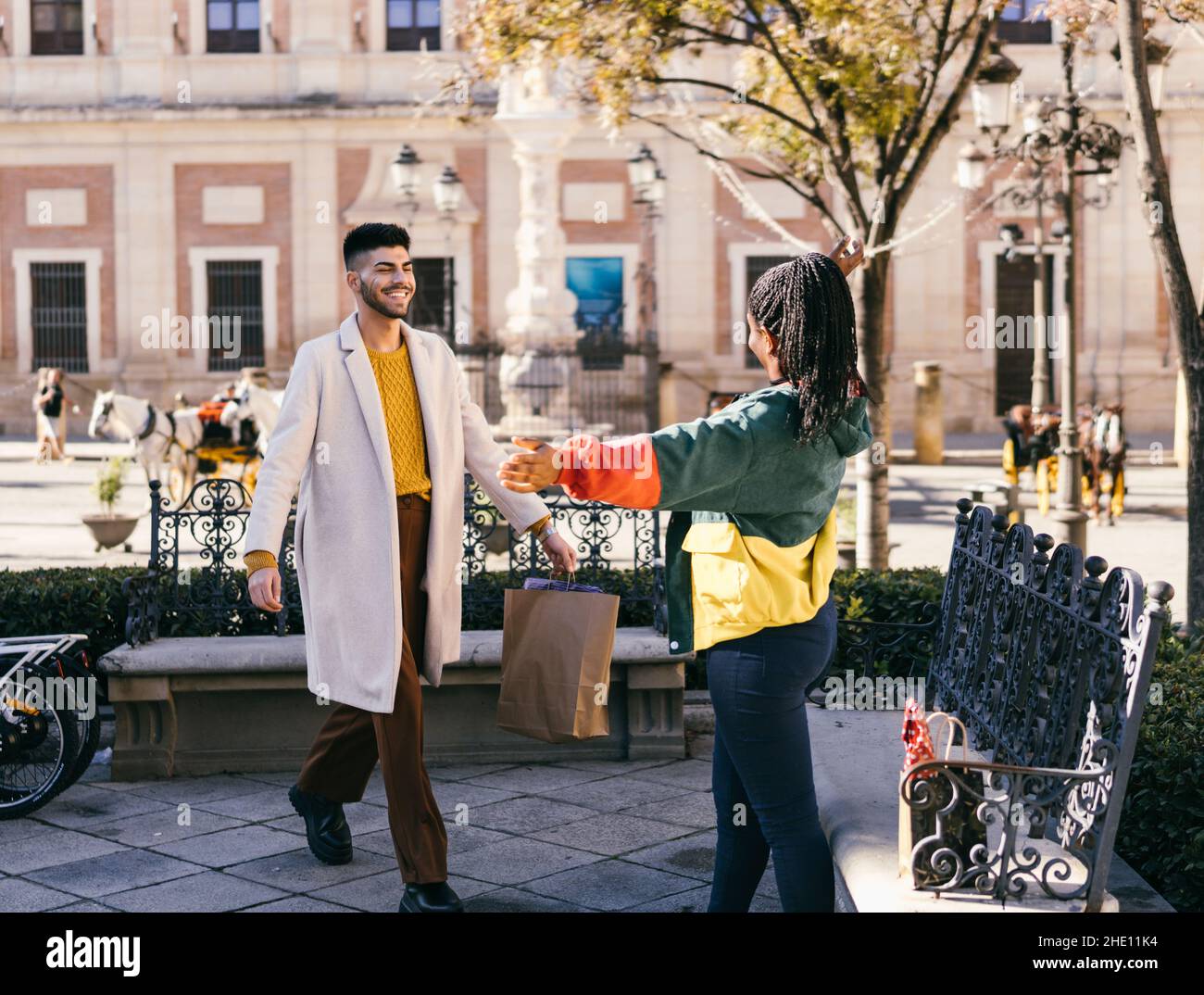 Donna africana che apre le braccia per abbracciare un uomo che arriva con un regalo all'aperto Foto Stock