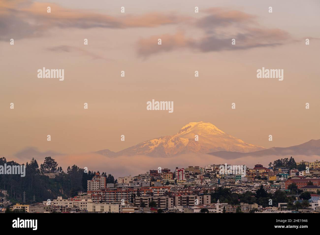 Paesaggio urbano di Quito al tramonto con il vulcano Cayambe innevato, Ande montagne, Ecuador. Foto Stock