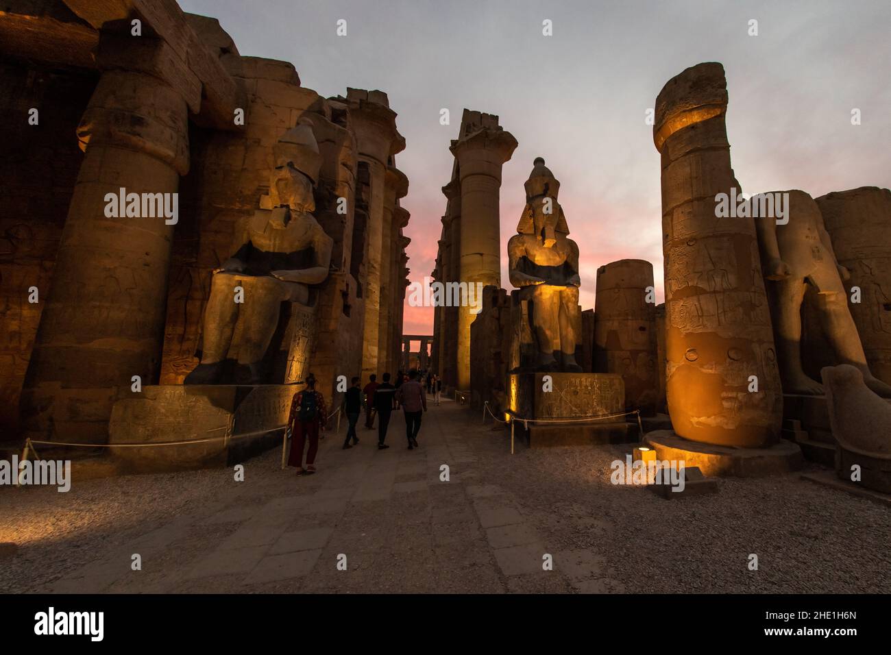 Statue e colonne al tempio di Luxor in Egitto illuminate da luci la sera, mentre l'oscurità cade per un effetto bello e drammatico. Foto Stock