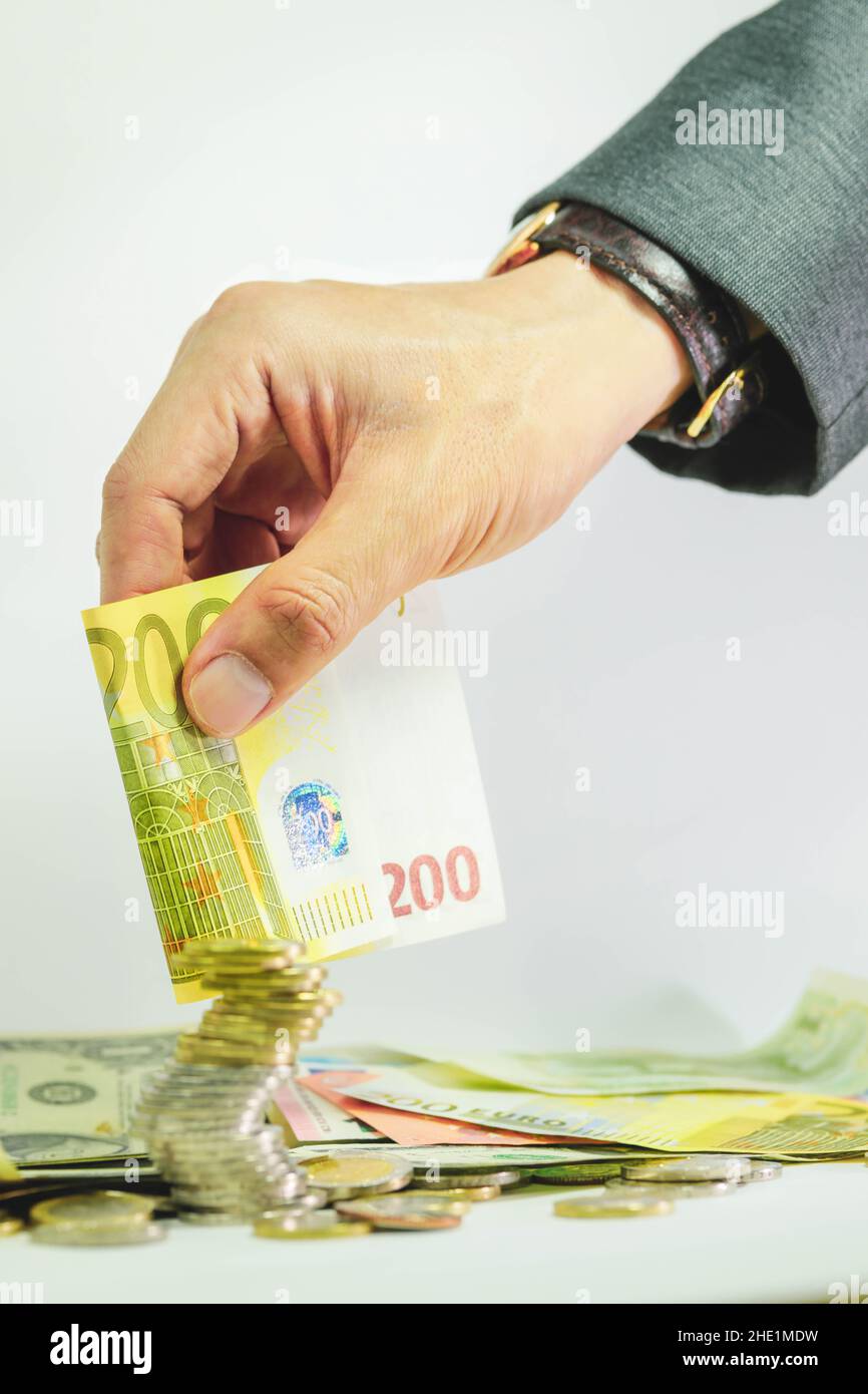Mano di uomo d’affari in possesso di moneta e monete da 200 euro Foto Stock