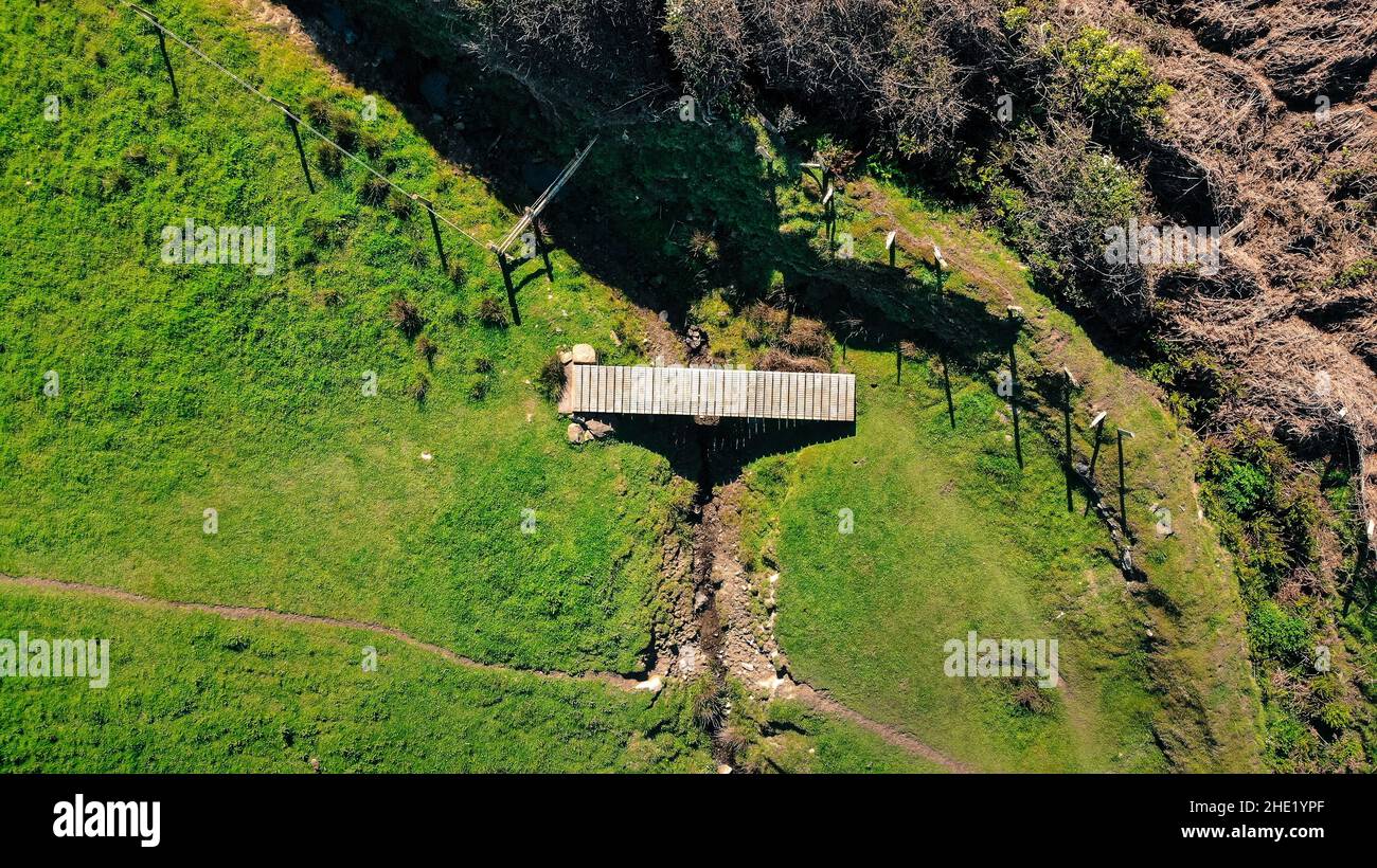 Immagine aerea di un ponte di legno lungo il Llanon, sentiero costiero Ceredigion. Mostra cespugli di gorse sullo sfondo e un ruscello Foto Stock
