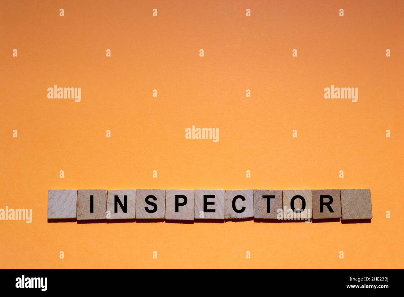ISPETTORE. Parola scritta su piastrelle quadrate di legno con sfondo arancione. Fotografia orizzontale. Foto Stock