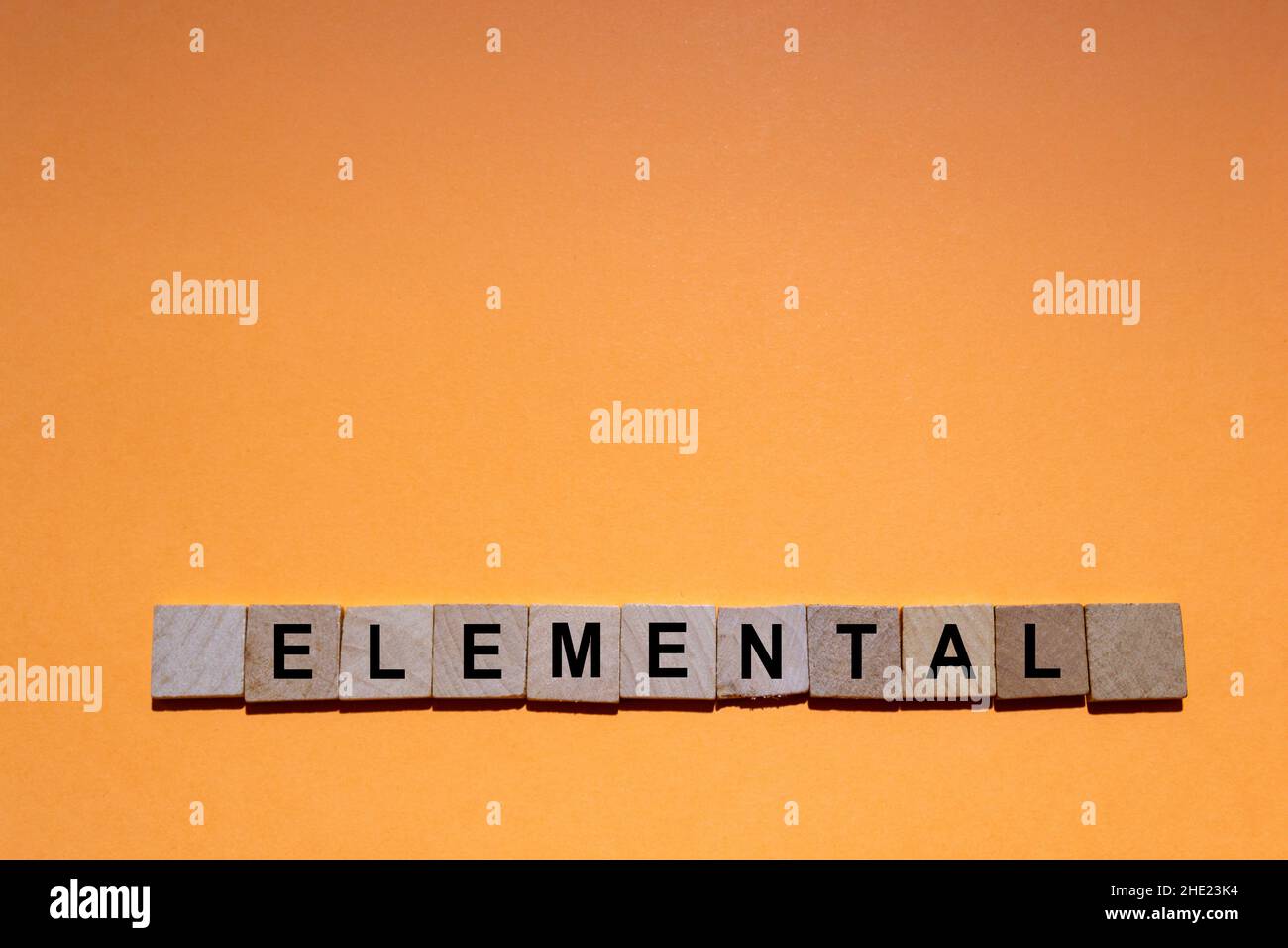 ELEMENTARE. Parola scritta su piastrelle quadrate di legno con sfondo arancione. Fotografia orizzontale. Foto Stock