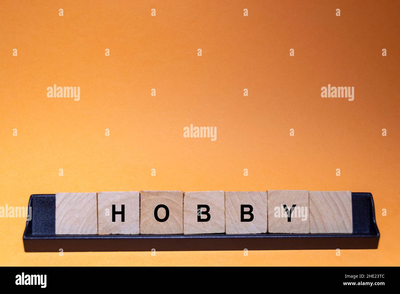 HOBBY. Parola scritta su piastrelle quadrate di legno con sfondo arancione. Fotografia orizzontale. Foto Stock