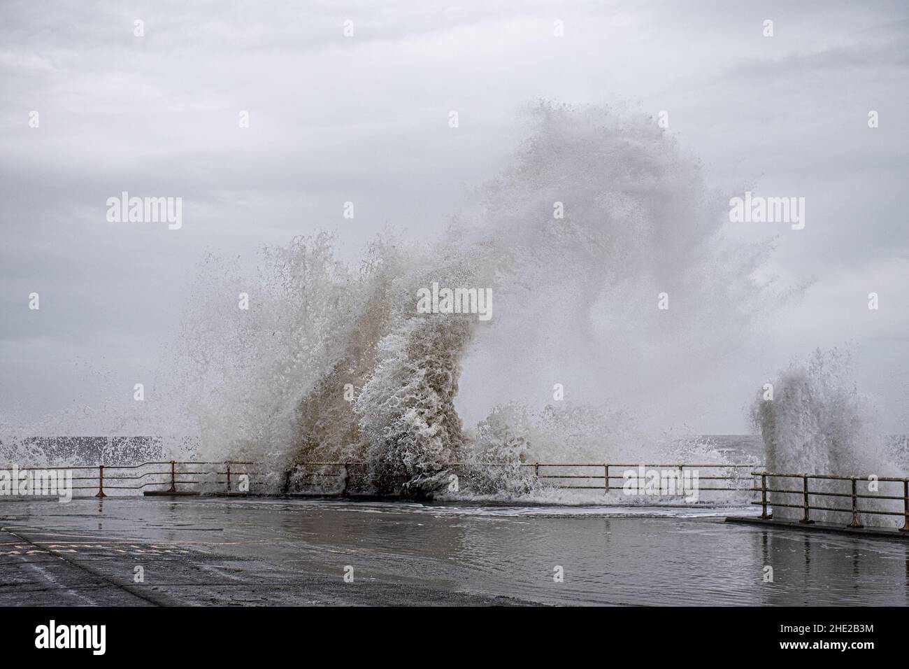 Le tempeste portano il tempo molto umido e ventoso al lungomare di Aberystwyth, metà Galles. Gli onlookers osservano nello stupore delle onde. Foto Stock