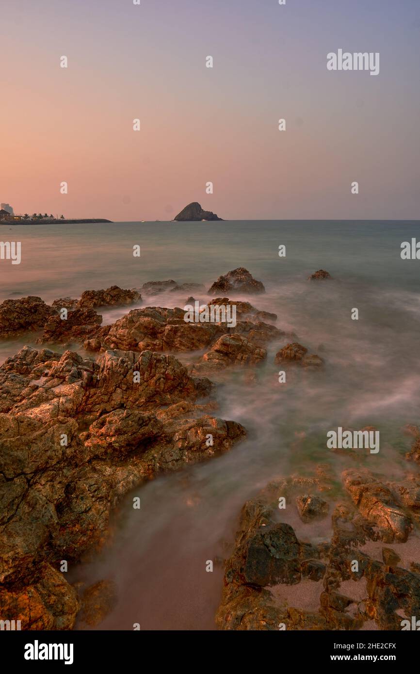 Un colpo verticale della zona rocciosa sopra l'acqua del lago contro un cielo chiaro al tramonto Foto Stock