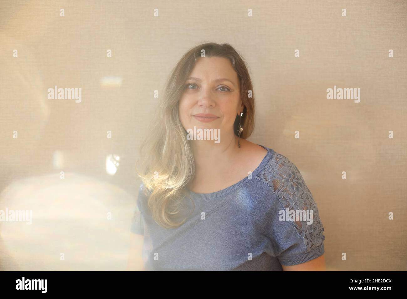 Amatevi ad ogni età. Donna di mezza età di 50s anni che tocca delicatamente il mento con la mano e guarda la macchina fotografica mentre si posa isolato su sfondo beige chiaro Foto Stock