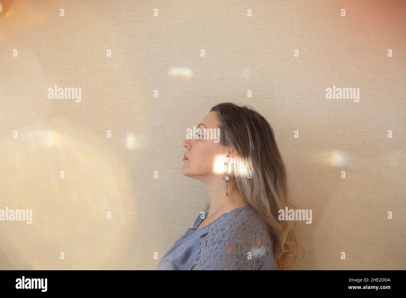Amatevi ad ogni età. Donna di mezza età di 50s anni che tocca delicatamente il mento con la mano e guarda la macchina fotografica mentre si posa isolato su sfondo beige chiaro Foto Stock