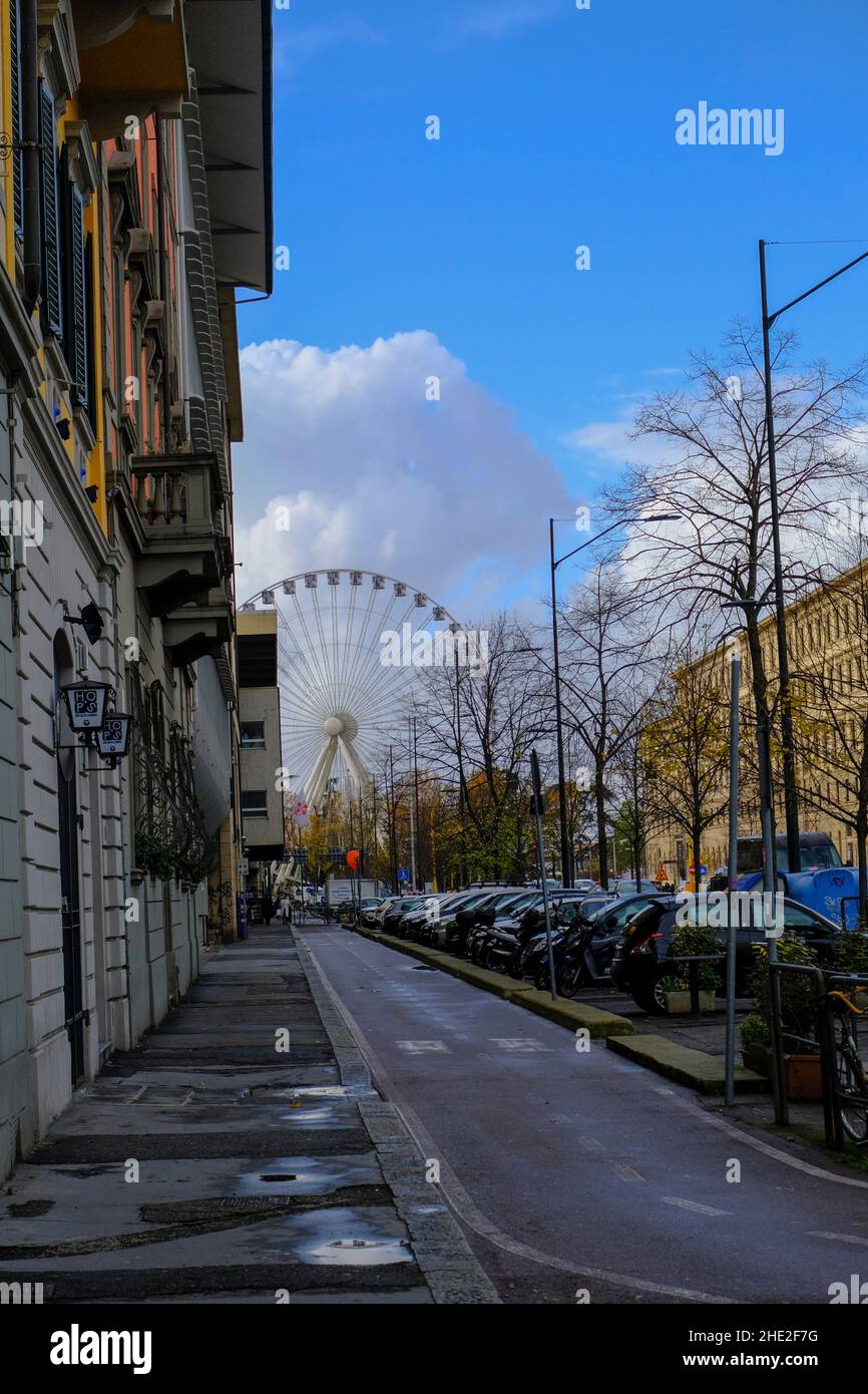 2021 dicembre Firenze 2021: Ruota panoramica nel parco attraverso il cielo blu, strada con edifici, e auto parcheggiate Foto Stock