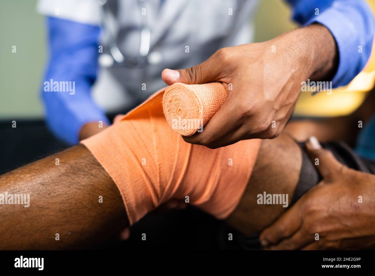 Primo piano di irriconoscibile medico disimballaggio stretch bendaggio dopo il recupero da pioggia di ginocchio o di vernice articolare dal paziente - concetto di pioggia di ginocchio Foto Stock