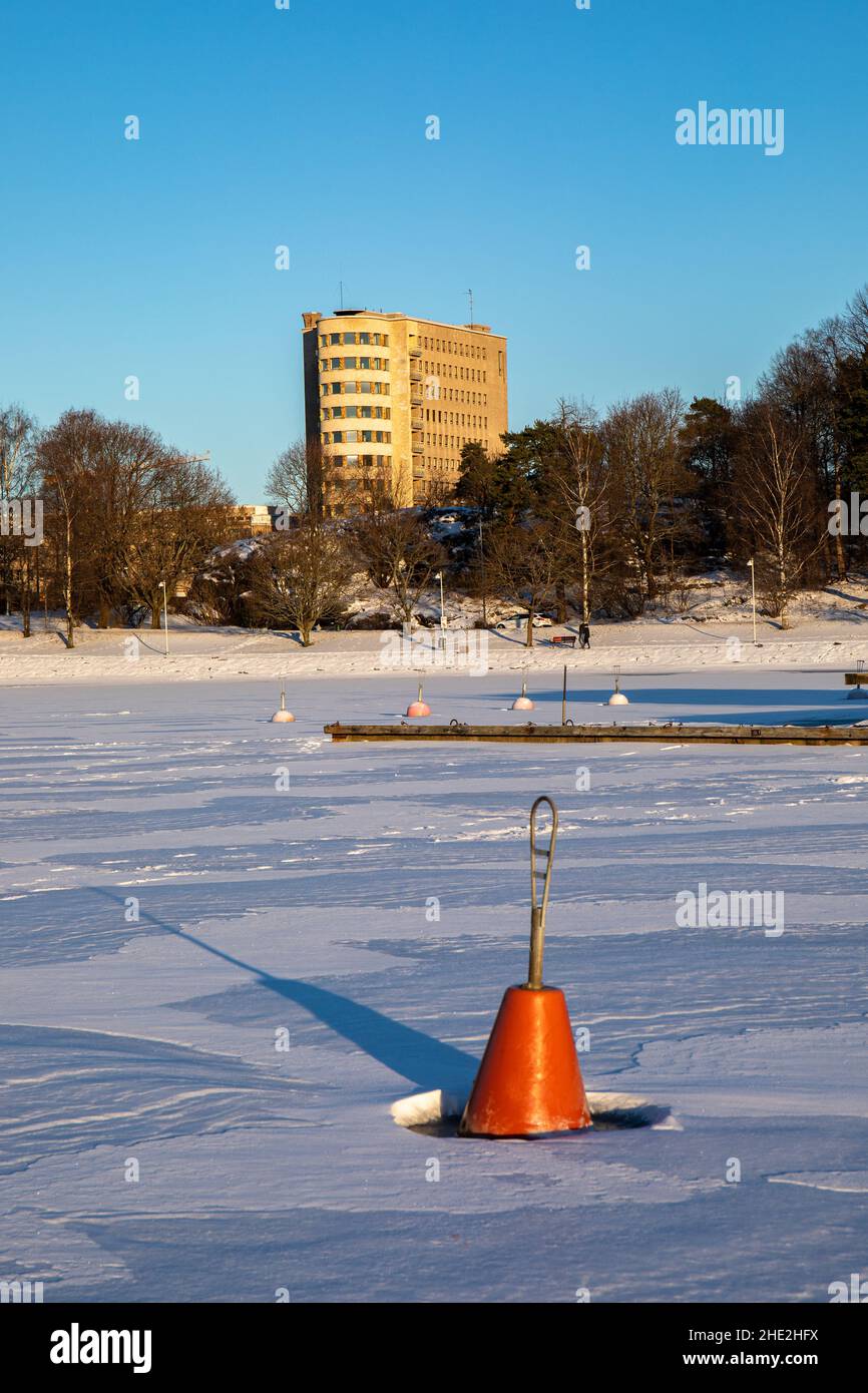 Boa di ormeggio sulla baia ghiacciata con Lastenlinna sullo sfondo a Helsinki, Finlandia Foto Stock
