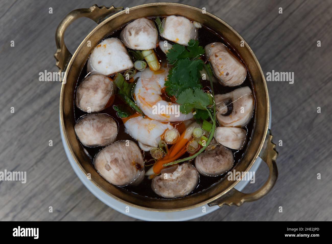 Vista dall'alto di una ciotola di ottone decorata ornata con zuppa di gamberi tom yung goong servita calda e pronta a slurp. Foto Stock