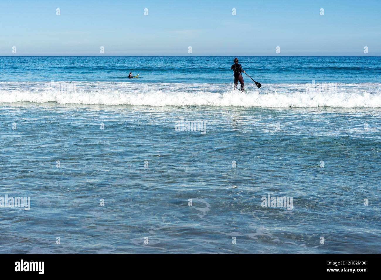 Impara a stare in piedi sulle onde dell'oceano in una giornata soleggiata e limpida a Canary Island Lanzarote Foto Stock