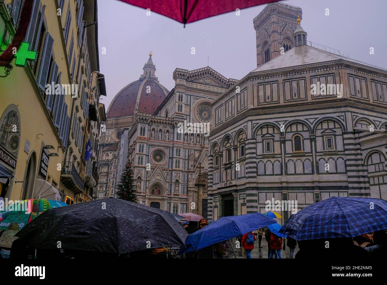 Firenze, Italia: Cupola di Santa Maria del Fiore da vicino attraverso il cielo drammatico, edifici, attraverso persone con ombrelloni in una giornata piovosa. Foto Stock