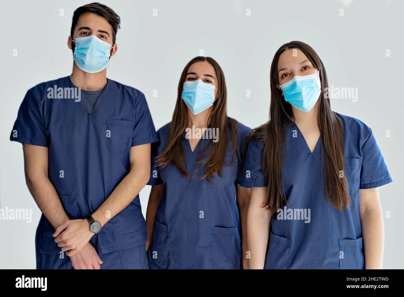 Giovani medici dentisti con maschere in uniforme blu scuro in piedi nel corridoio Foto Stock