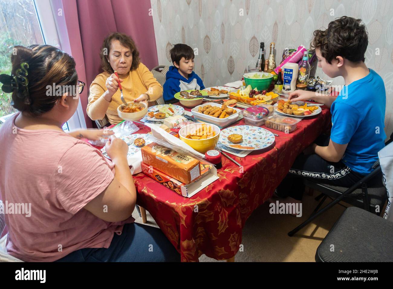 Una famiglia si siede al tavolo della sala da pranzo e mangia insieme con un pasto in stile buffet con una selezione di diversi piatti tra cui scegliere Foto Stock