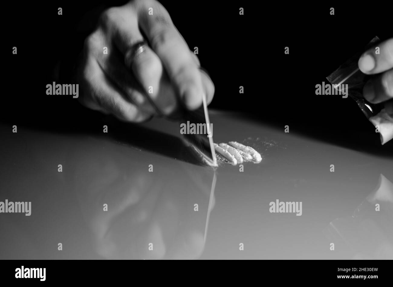 L'uomo divide la cocaina in strisce e poi russava. Concetto di narcotici. Versione in bianco e nero. Foto Stock