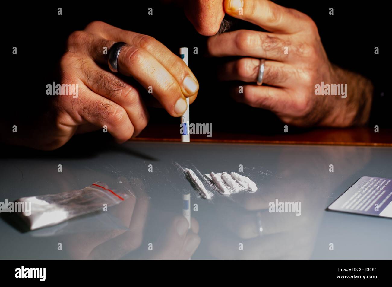 Quest'uomo sta russando la polvere di cocaina con la banconota laminata. Concetto di narcotici. Foto Stock