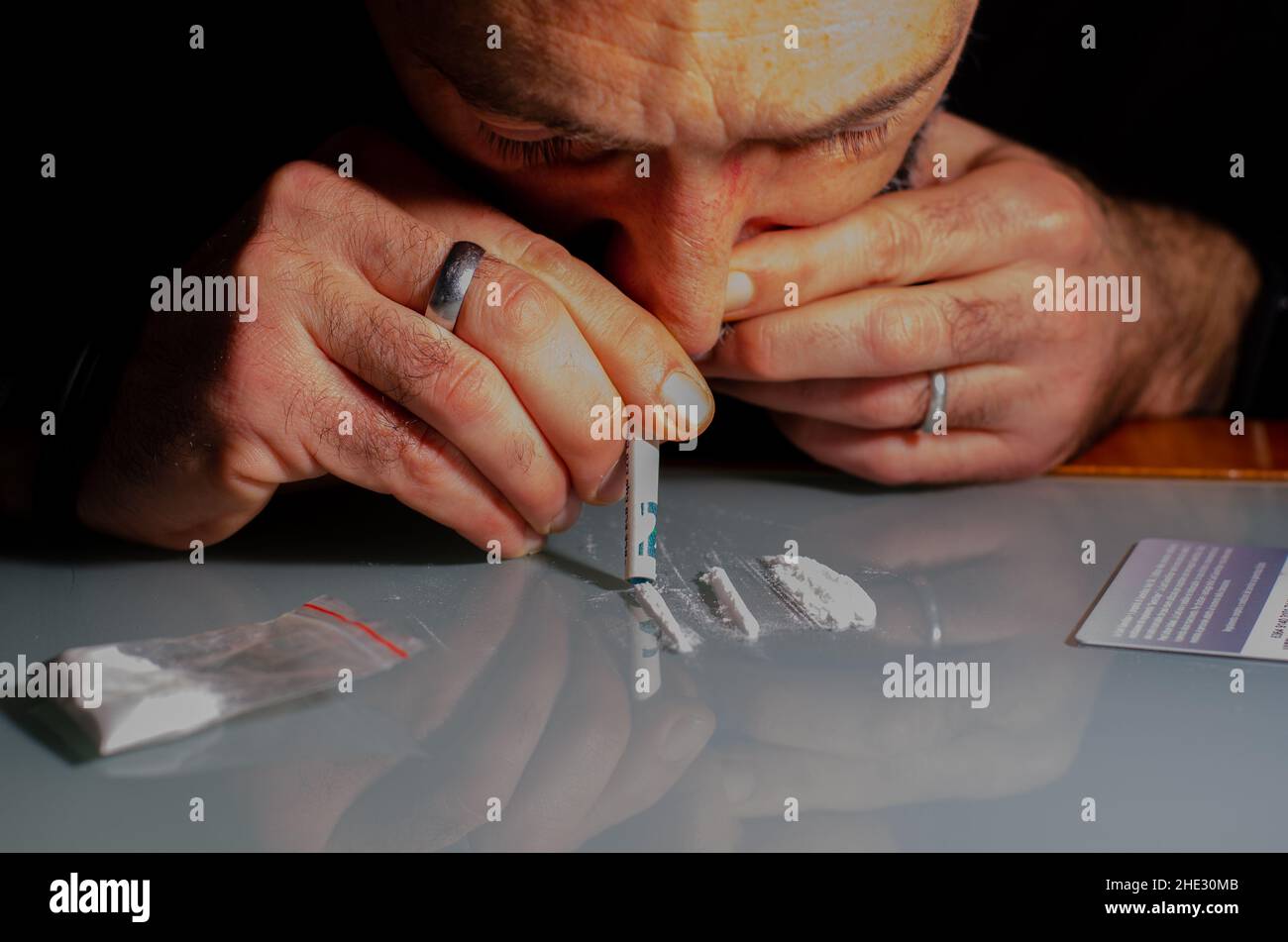 Quest'uomo sta russando la polvere di cocaina con la banconota laminata. Concetto di narcotici. Foto Stock