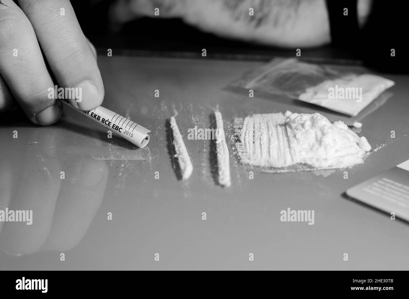 L'uomo sta per snort la cocaina con la banconota arrotolata. Concetto di narcotici. Versione in bianco e nero. Foto Stock