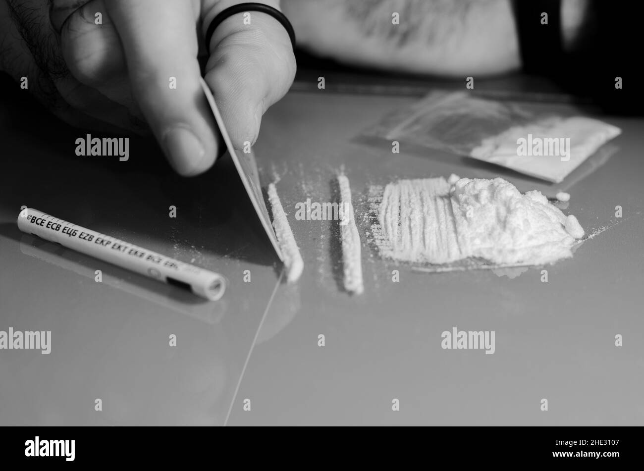 L'uomo divide la cocaina in strisce e poi russava. Concetto di narcotici. Versione in bianco e nero. Foto Stock