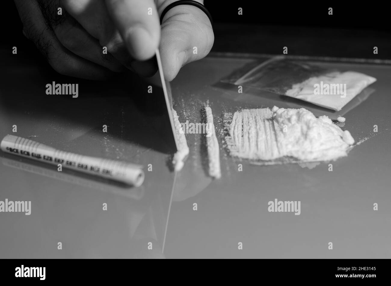 L'uomo divide la cocaina in strisce e poi russò. Concetto narcotico. Versione in bianco e nero. Foto Stock