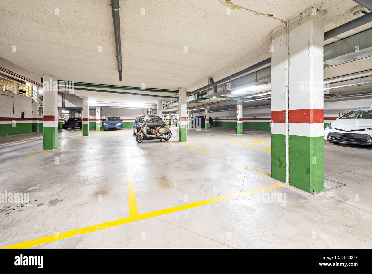Garage con pista di cemento in condominio residenziale con auto e biciclette Foto Stock