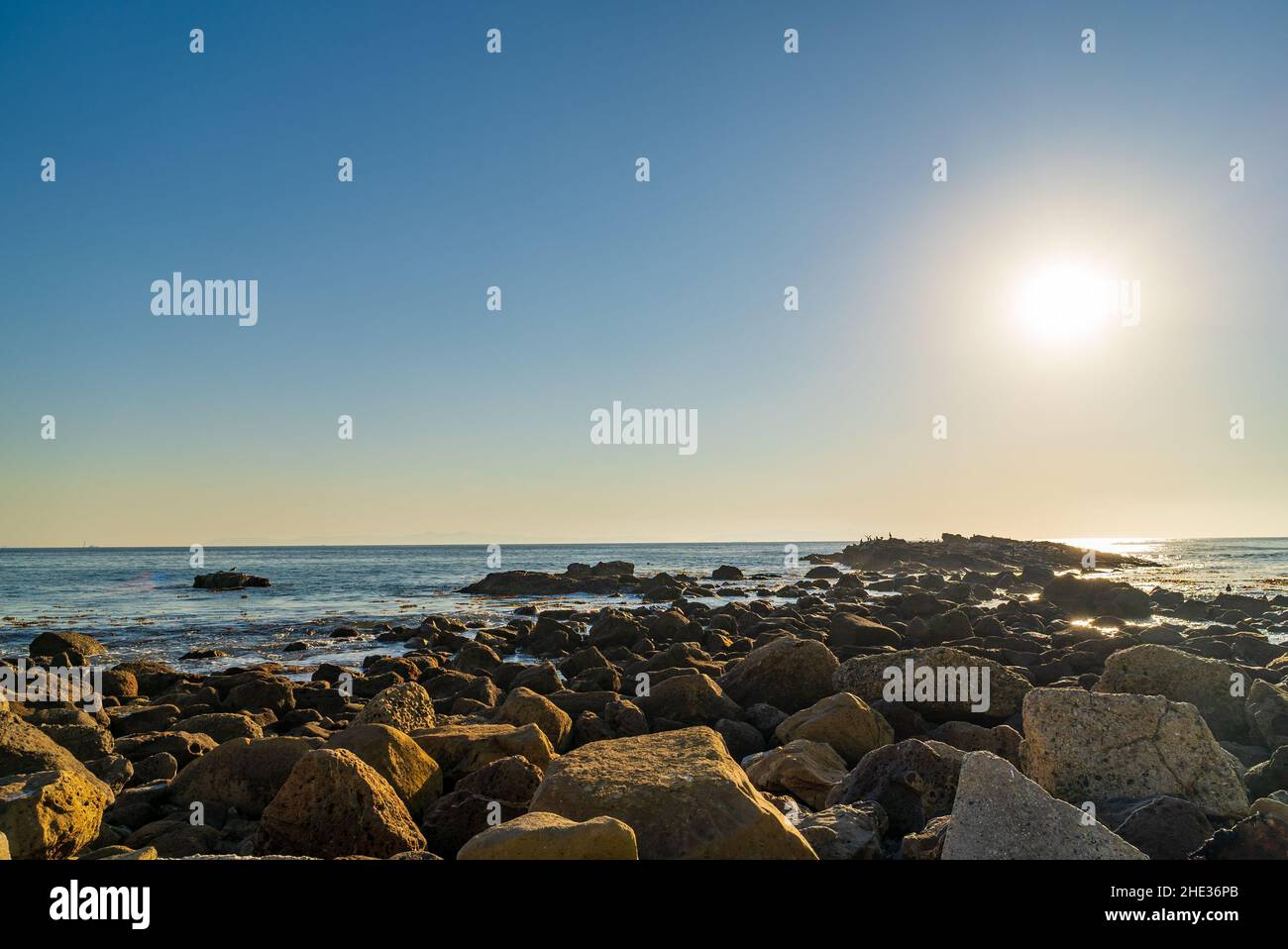 Splendida vista sul sole che brilla sul mare e sulla costa rocciosa Foto Stock