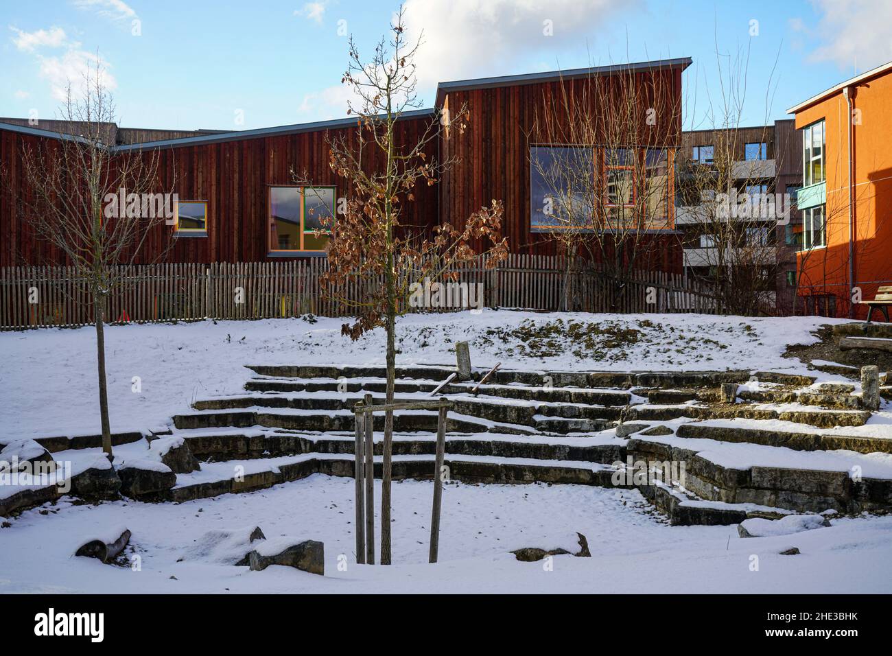 Piazzale con posti a sedere in pietra ricoperti di neve in un edificio scolastico del Campus Rudolf Steiner Waldorf School di Monaco in inverno. Foto Stock
