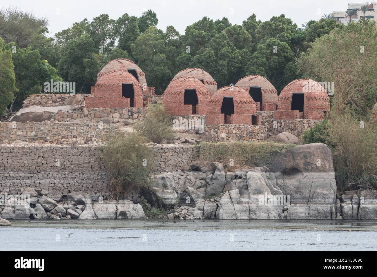 Case in mattoni rossi che sono state costruite illegalmente lungo il fiume Nilo nella città di Assuan, Egitto e ora si siedono vuoti in attesa di demolizione. Foto Stock