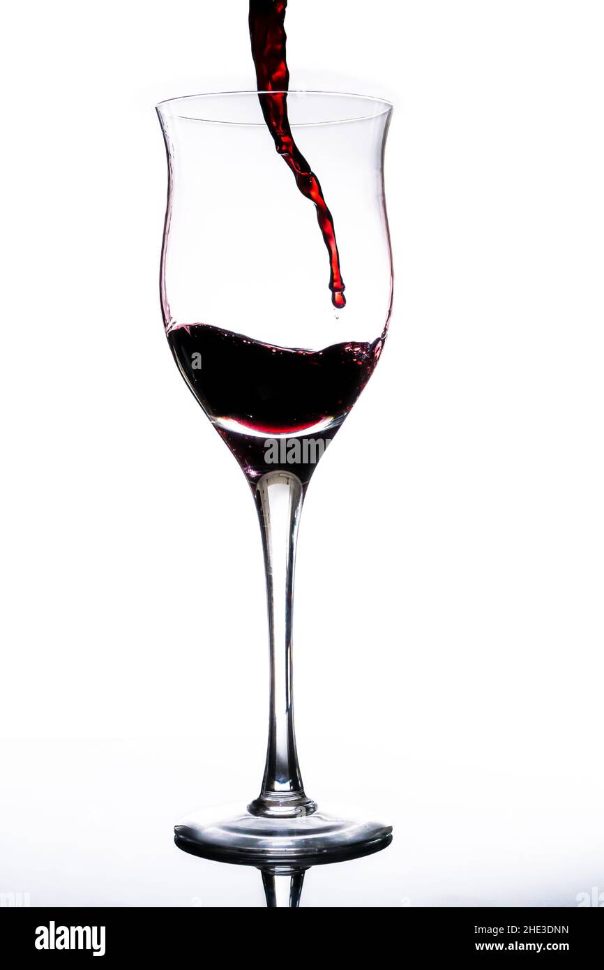 Serve un bel bicchiere di vino rosso. Fondo bianco, bicchiere di vetro. Eleganza, buon gusto, concetto di stile. Foto Stock