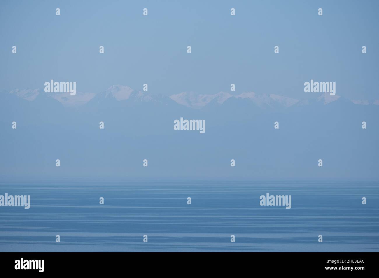 Impressionante catena montuosa di Tian Shan innevata dietro l'acqua blu del lago Issyk-Kul, Kirghizistan Foto Stock