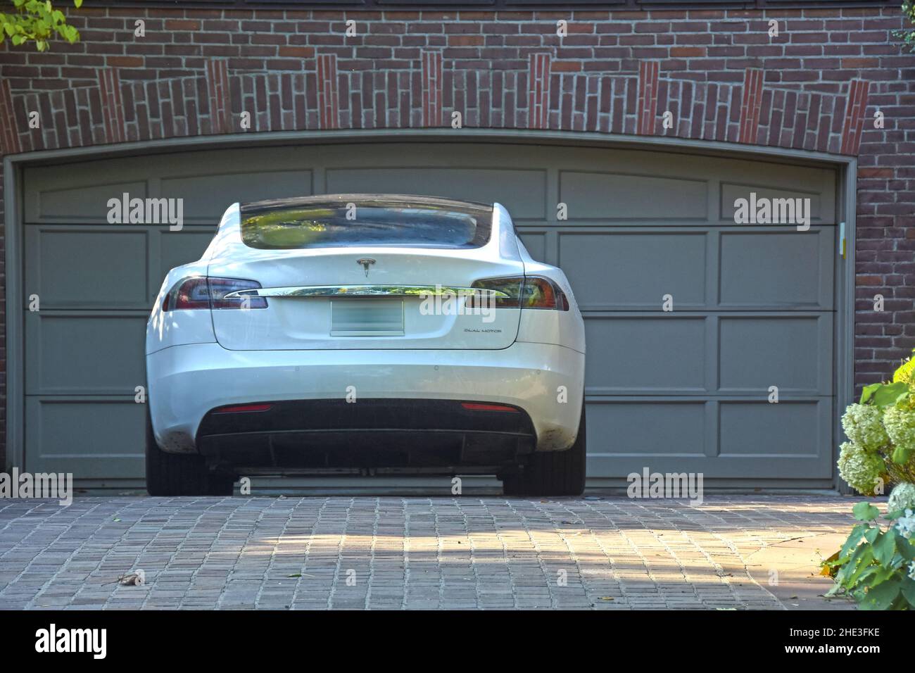 Parcheggio Tesla di fronte al garage della casa. Foto Stock