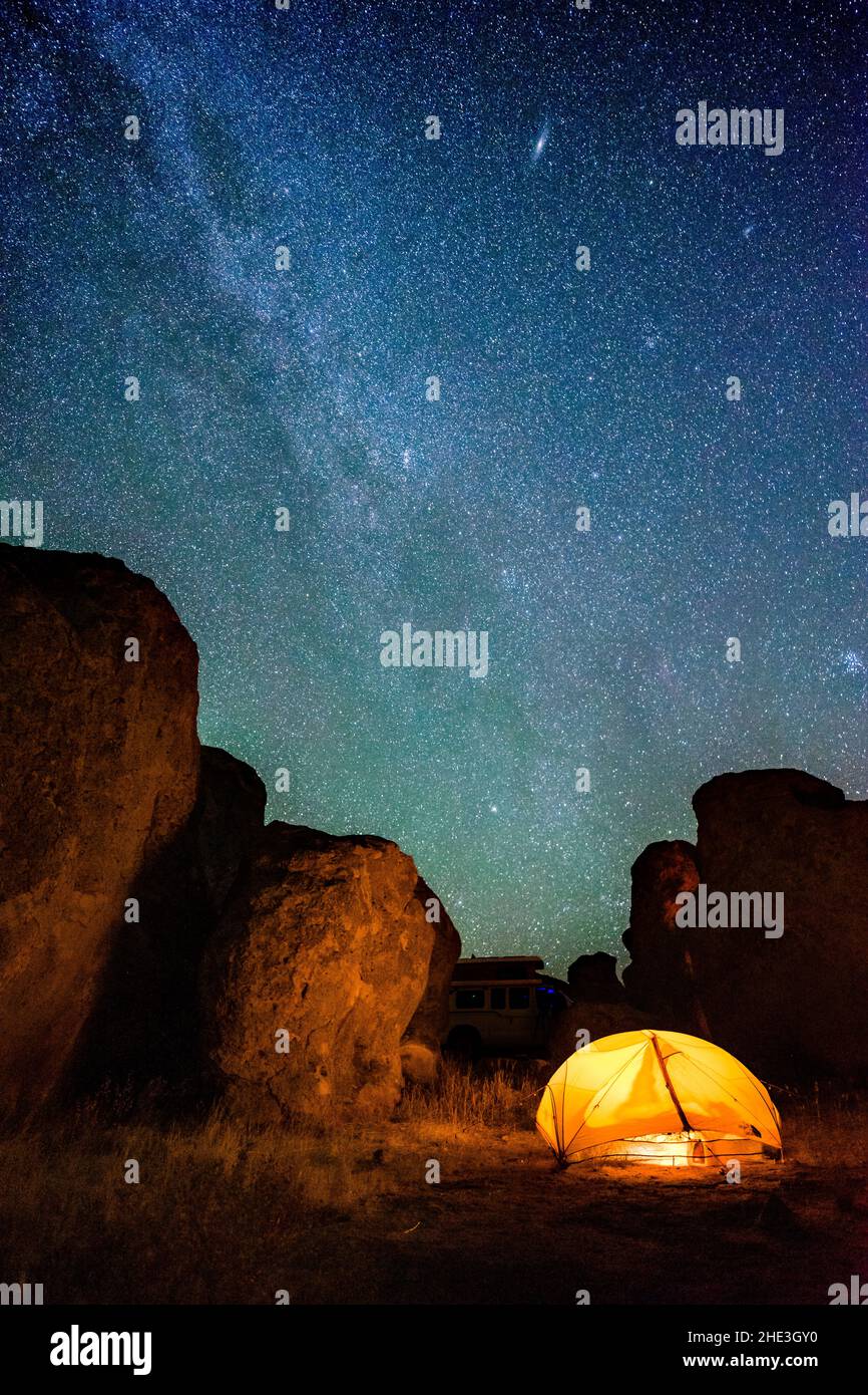 La Via Lattea e altre stelle nel cielo notturno sopra le formazioni rocciose e la tenda incandescente al Parco Sate della Città delle rocce, New Mexico. Foto Stock