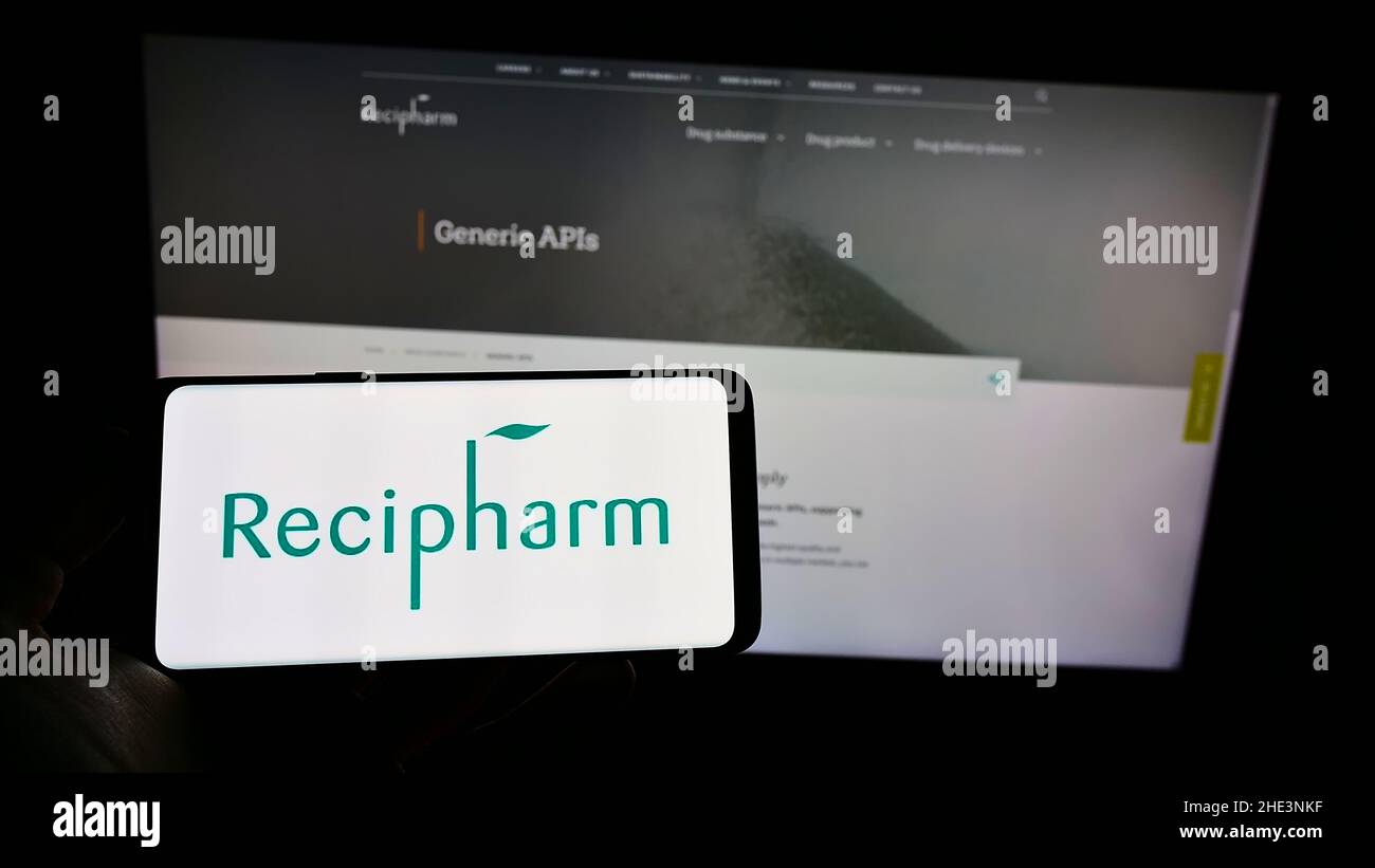 Persona che tiene il cellulare con il logo di svedese Pharmaceutical Recipharm AB sullo schermo di fronte al sito web aziendale. Mettere a fuoco sul display del telefono. Foto Stock