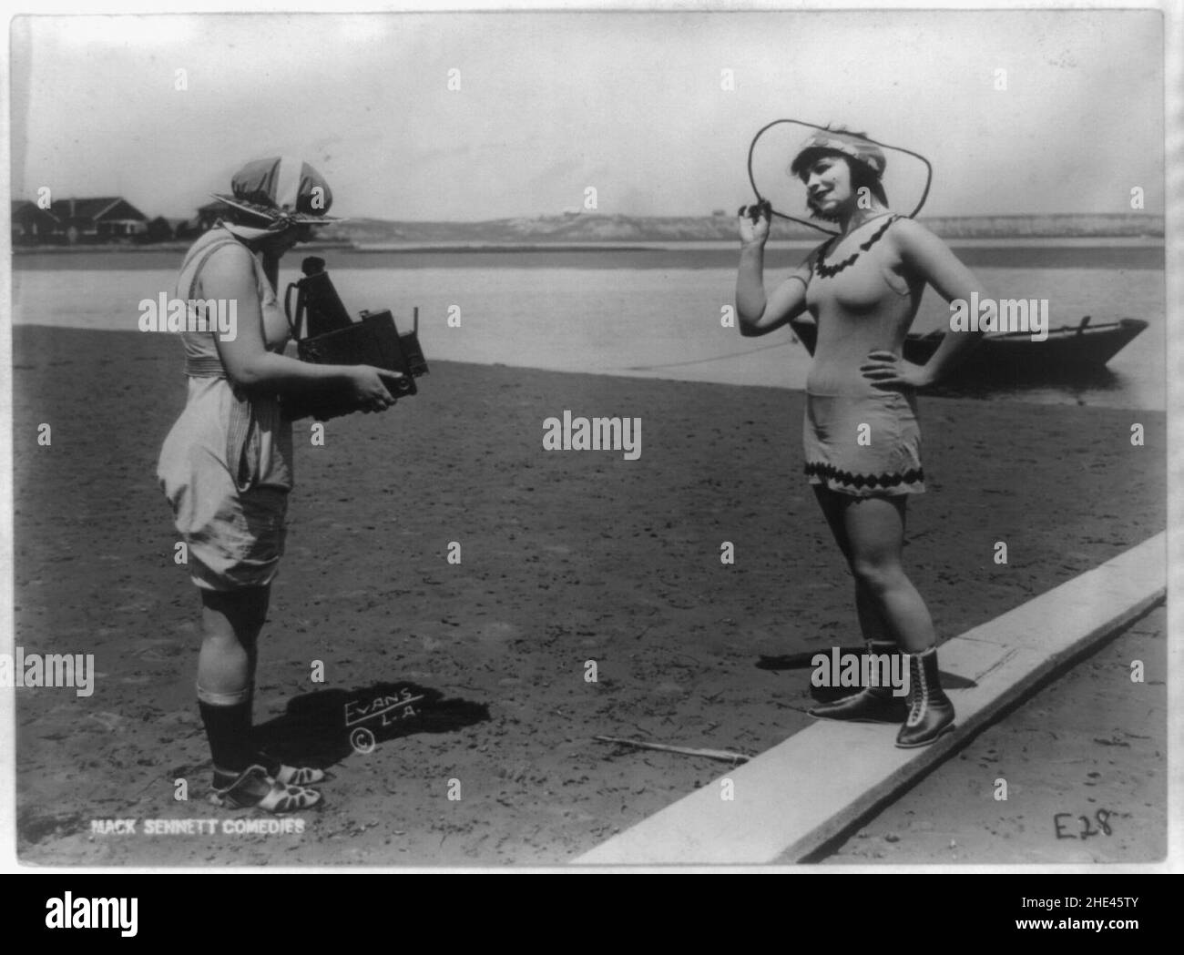 Roxy McGowan e Mary Thurman in costume da bagno, con uno che prende la foto dell'altro sulla spiaggia, posato per Mack Sennett Productions) - Evans Studio, L.A Foto Stock