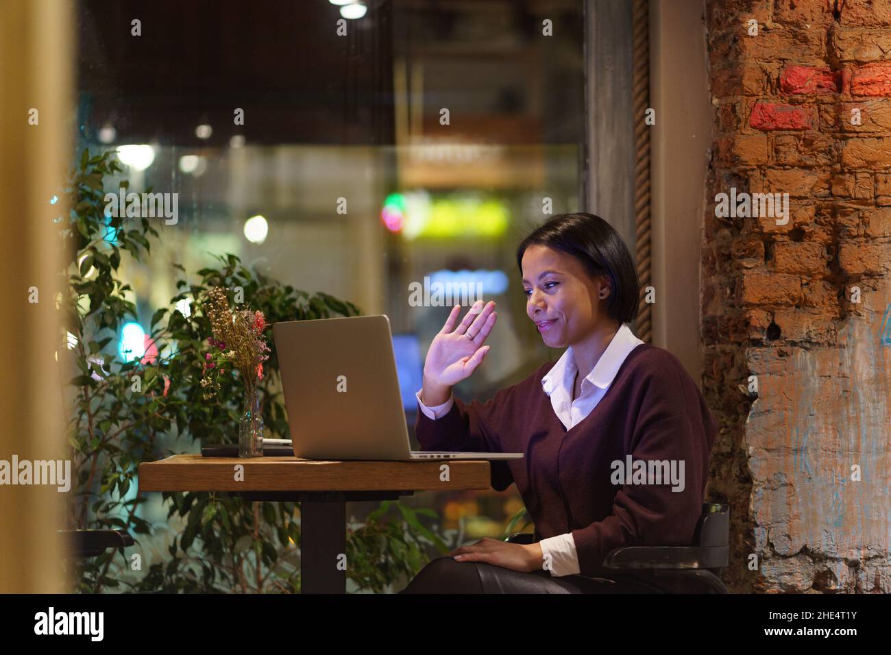 Giovane ragazza afroamericana che lavora da remoto in un bar, dando lezioni online via laptop Foto Stock