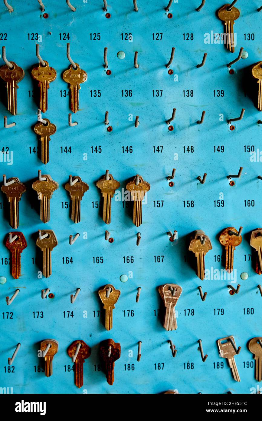 Vecchie chiavi vuote sul pannello blu con ganci 1, vista frontale Foto Stock